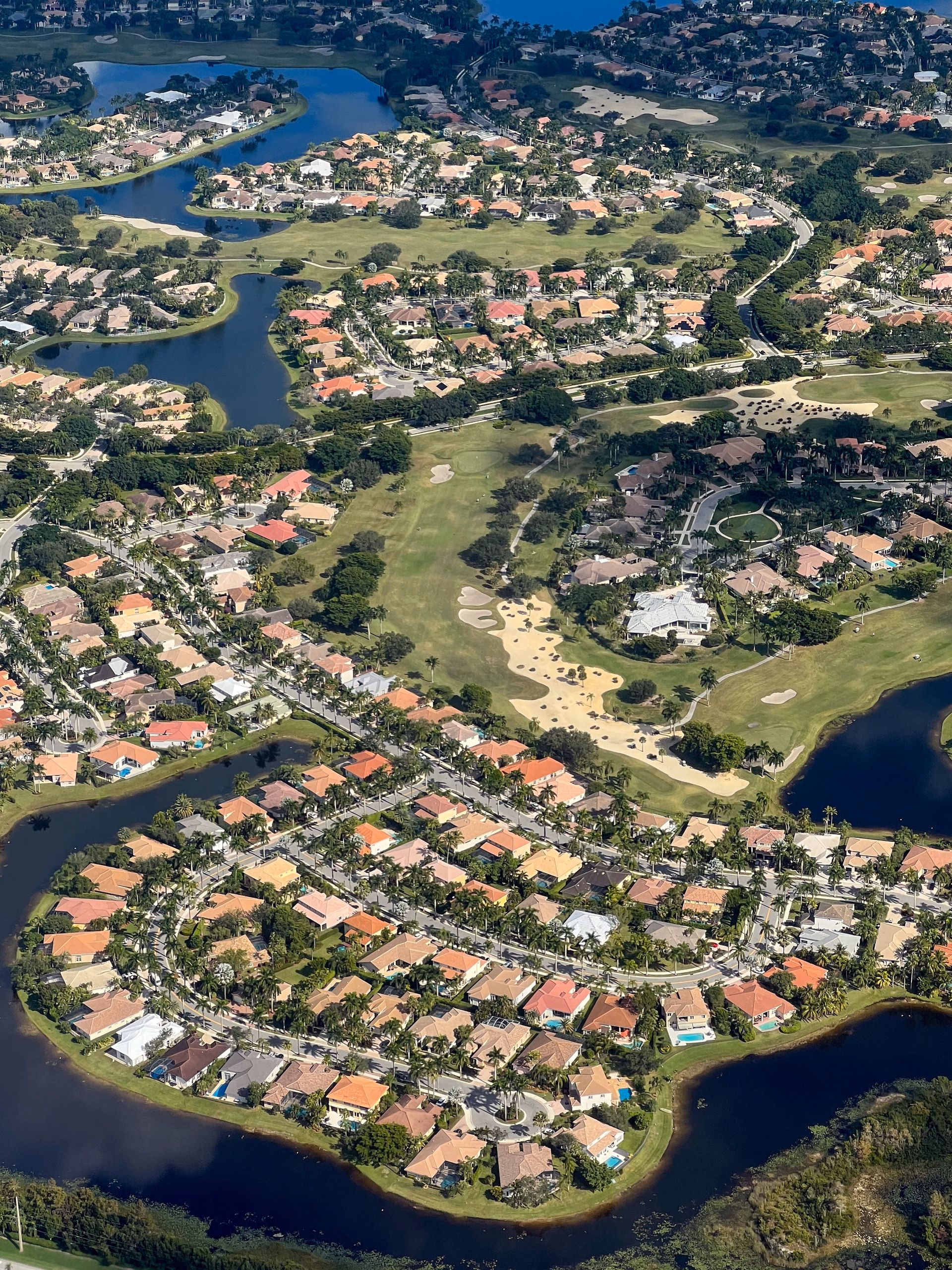 Aerial view of a residential area with houses, golf course, and water bodies in Wellington, Florida.